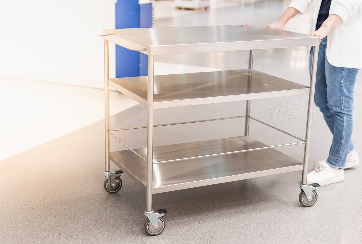 Female hand pushing the stainless steel food trolley cart to the move a lot of parcels.