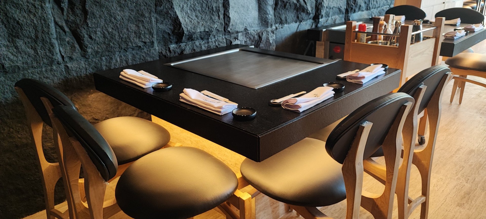 Modern dining table with black top and yellow/gold upholstered chairs in a contemporary interior setting