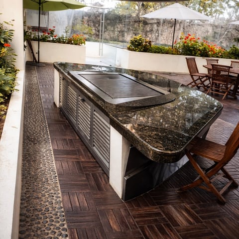Patio exterior con encimera integrada de piedra, cocina, sillas de comedor de madera, maceteros y sombrillas en tarima de madera