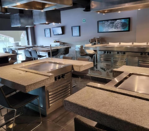 Modern commercial kitchen with granite countertops, stainless steel appliances, and multiple workstations