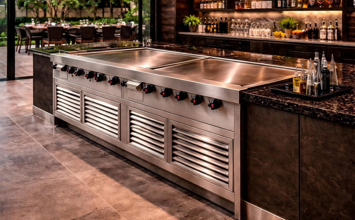 Stainless steel outdoor kitchen counter with built-in cooktop, griddle, and louvered cabinets, featuring bar seating and landscape views